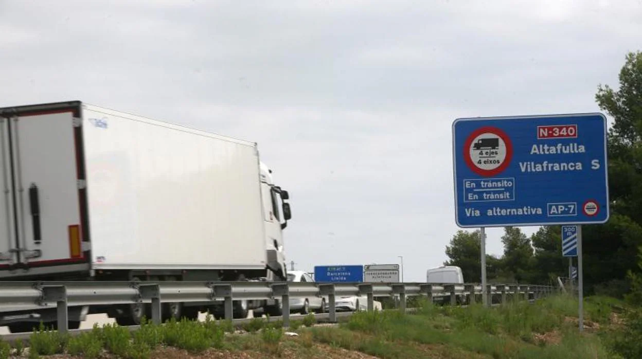 Camiones circulan junto a la señal que anuncia su desvío obligatorio desde la carretera nacional a la auotpista