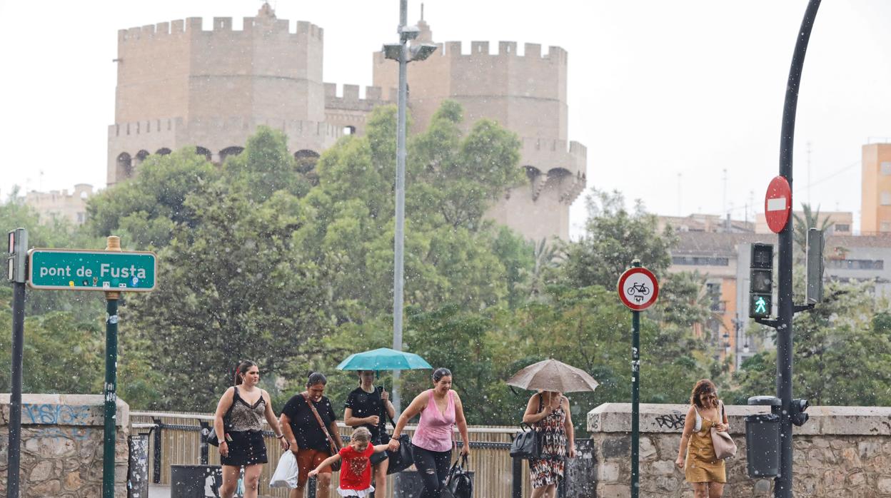 Varias personas se protegen de la lluvia en el centro de Valencia