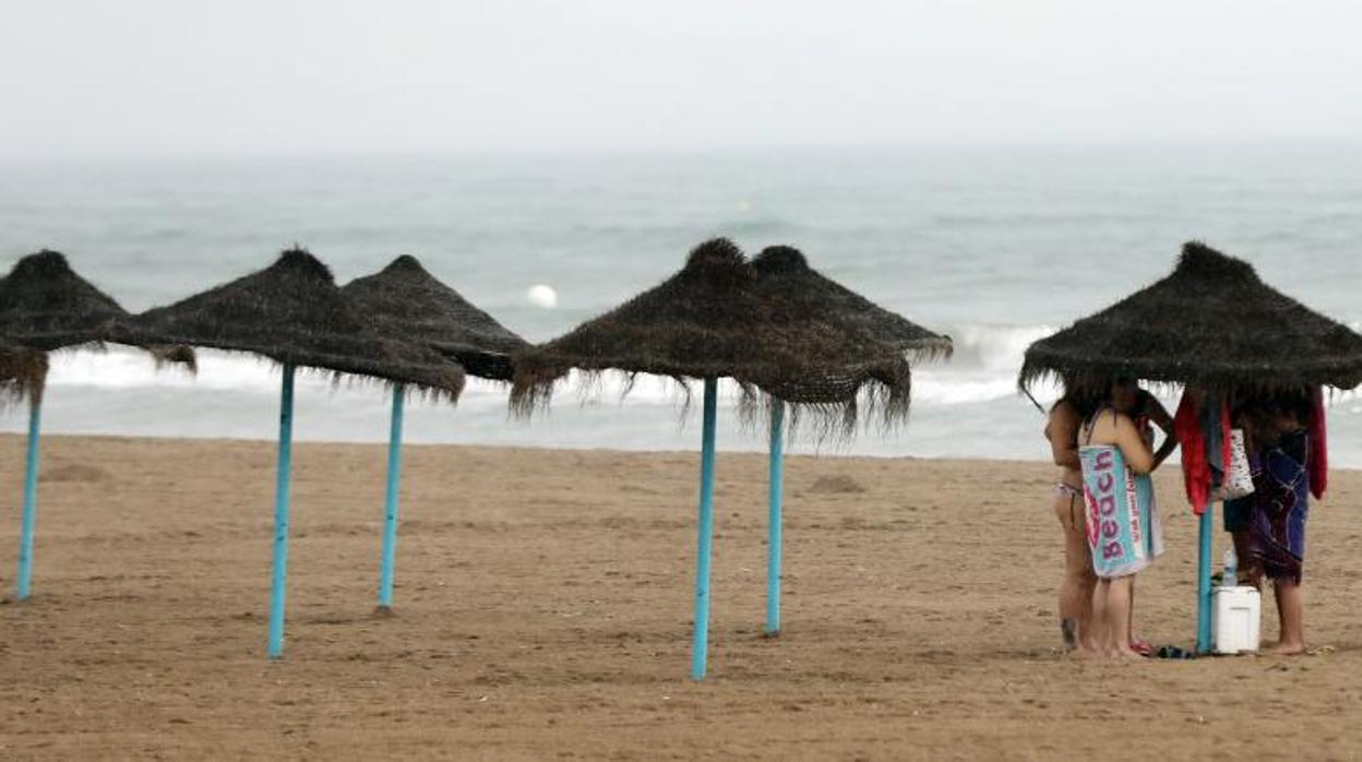 Bañistas se protegen de la lluvia este domingo en la playa