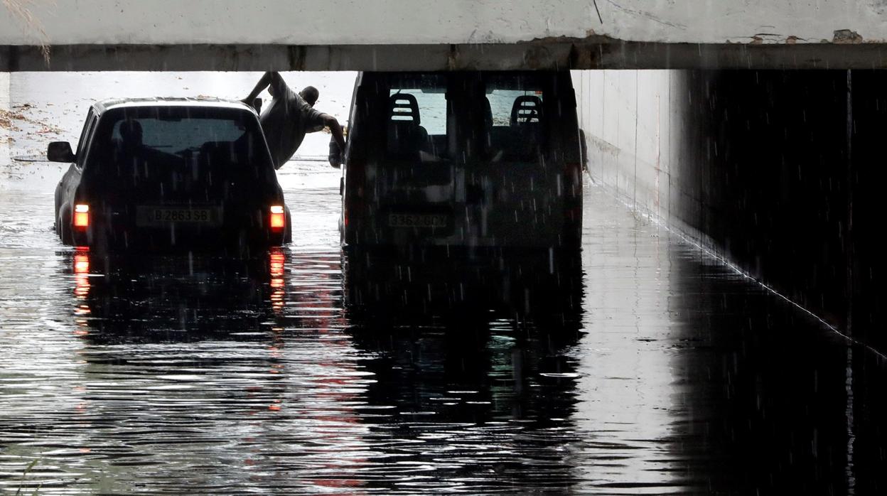Una persona trata de salir de su coche, atrapado por las lluvias en Valencia