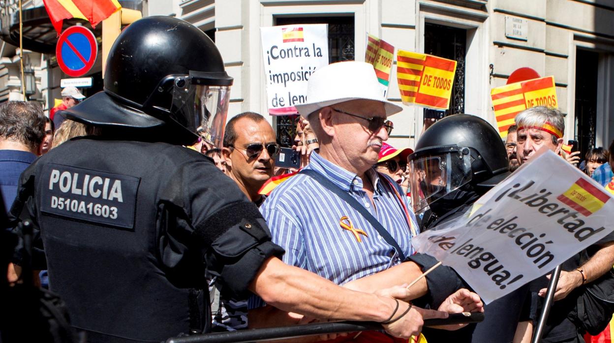 Efectivos de la policía impiden el paso a un grupo de personas hacia la plaza de Sant Jaume para asistir a la concentración convocada por la asociación Hablamos Español