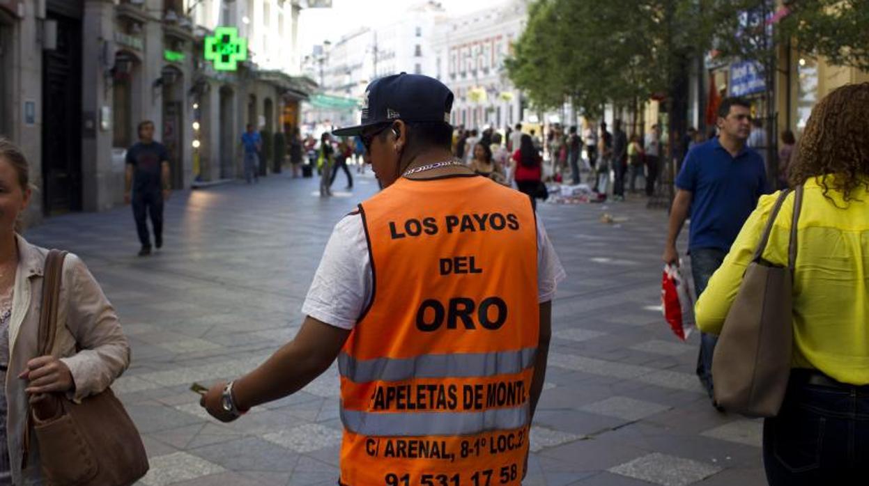 Un hombre reparte publicidad de un establecimiento de compraventa de oro en la calle de Arenal