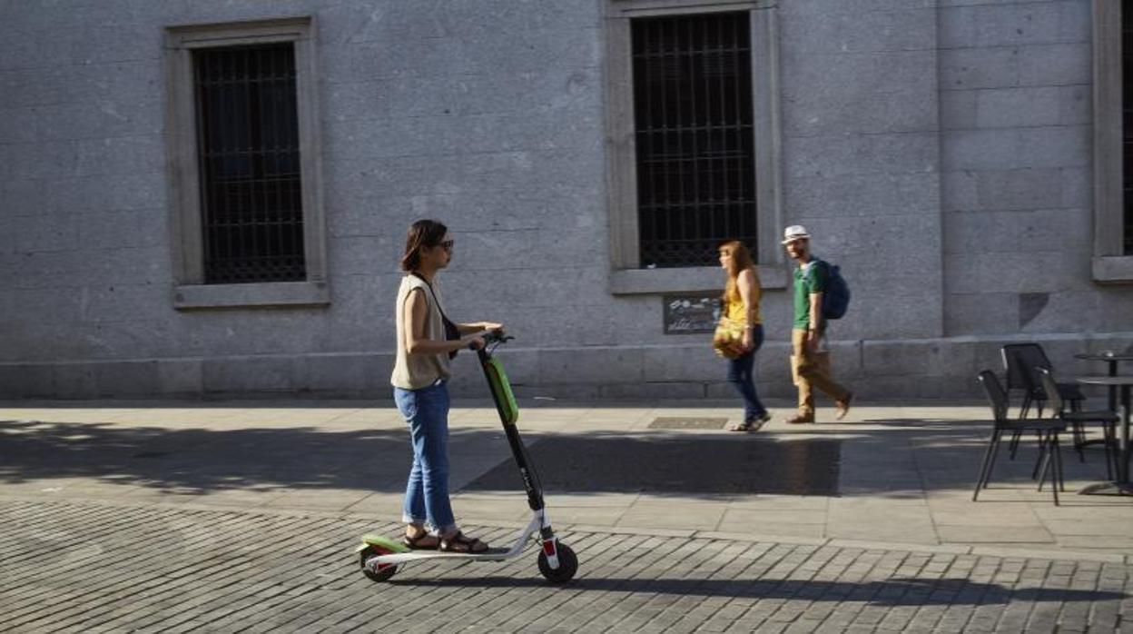 Una usuaria de un patinete eléctrico circula por la zona de Ópera