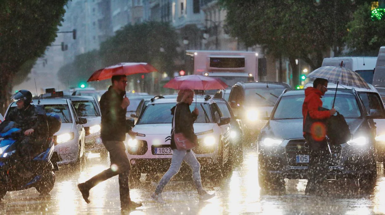 Varias personas se protegen de la lluvia en Valencia