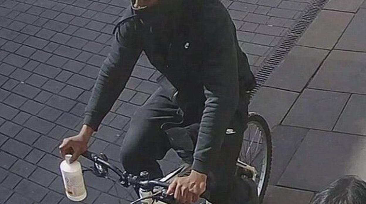 Foto de archivo de un hombre con una botella de ácido por la calle en bicicleta