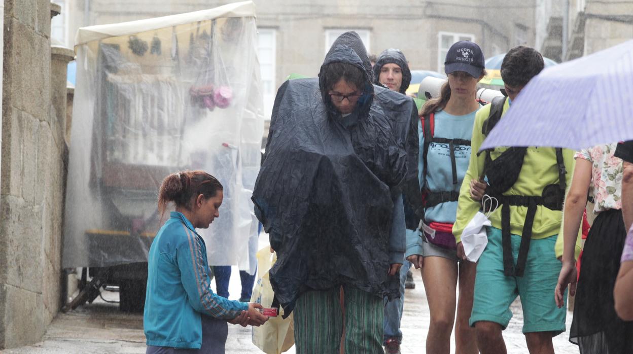 Una joven pide limosna bajo la lluvia, en Santiago