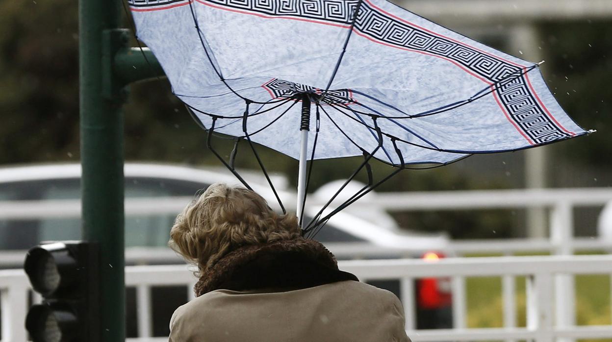 Una mujer trata de sujetar el paraguas, zarandeado por las fuertes rachas de viento