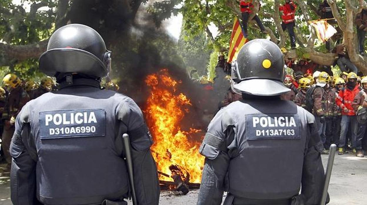 Dos mossos contemplan una hoguera encendida por los bomberos en las protestas frente al Parlament