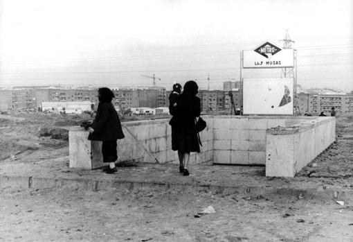 Estación de Metro «Las Musas» en 1975: una viajera se remanga los pantalones para poder llegar a los edificios con el menor barro posible