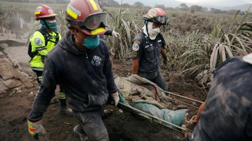 Bomberos cargando con un cuerpo en la zona afectada por el Volcán de Fuego