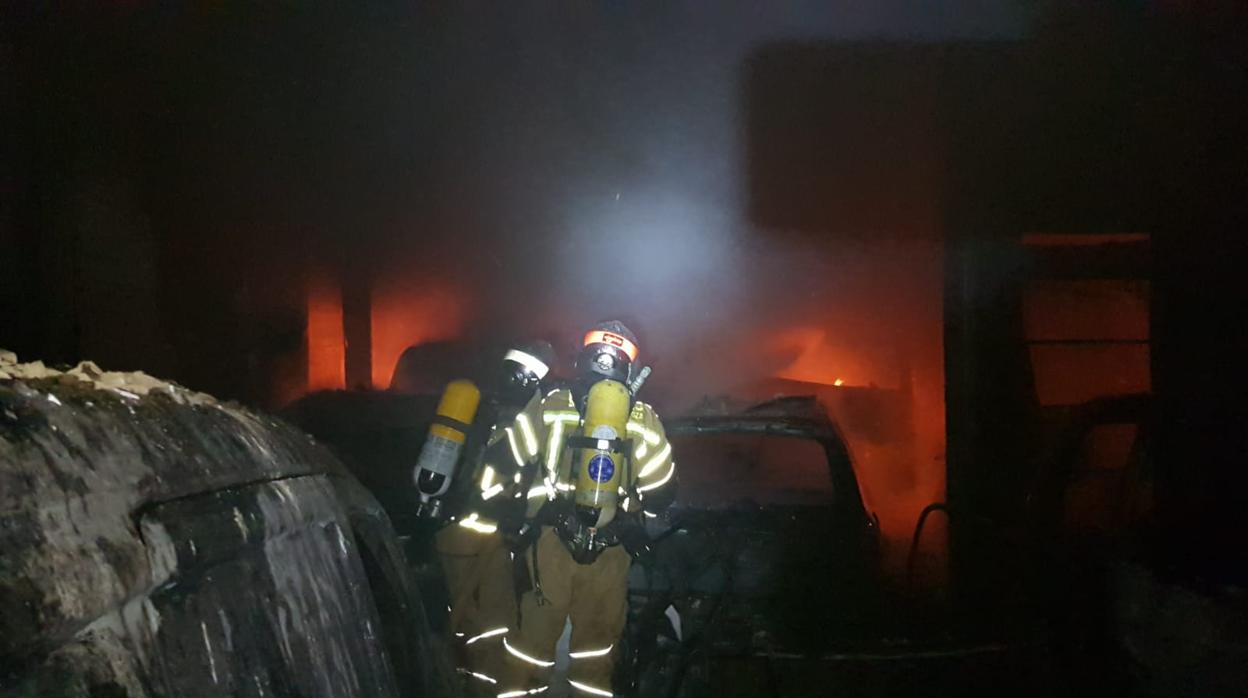 Los bomberos, mientras luchaban contra el fuego en el taller que ha quedado arrasado