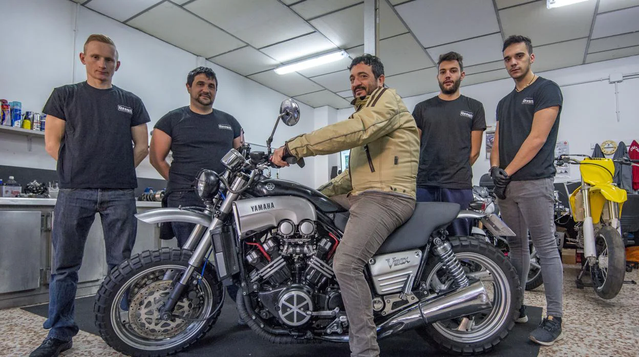 Roberto Dengra, a los mandos de su moto y rodeado por los mecánicos que la han customizado