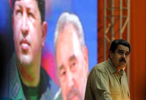 Nicolás Maduro en un acto público, con la imagen detrás de Hugo Chávez y Fidel Castro