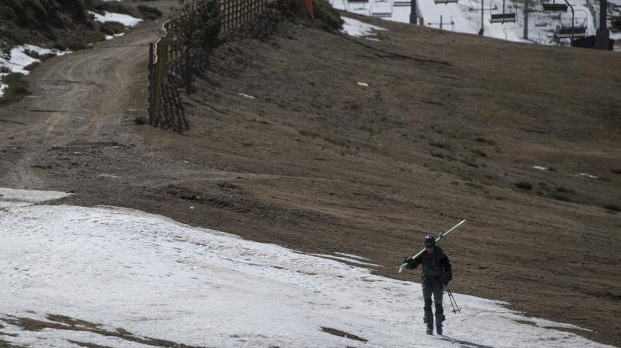 Un esquiador camina entre nieve y barro en Valdesquí