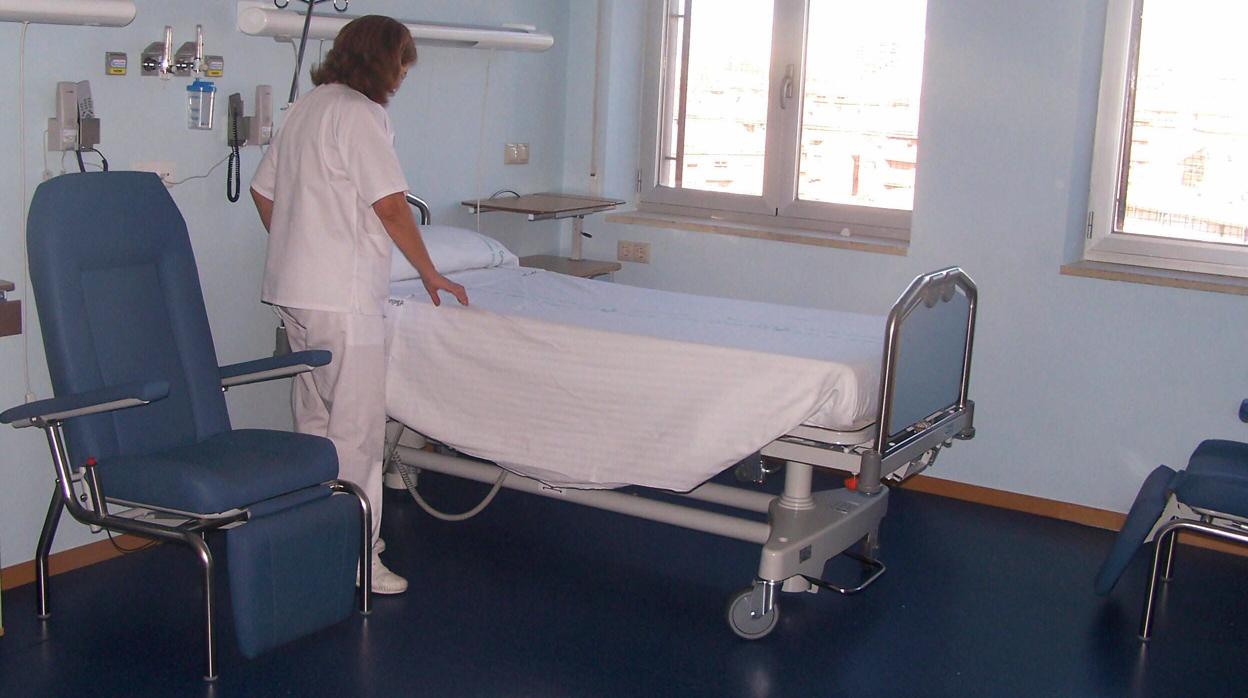 Una trabajadora sanitaria preparando una cama de hospital