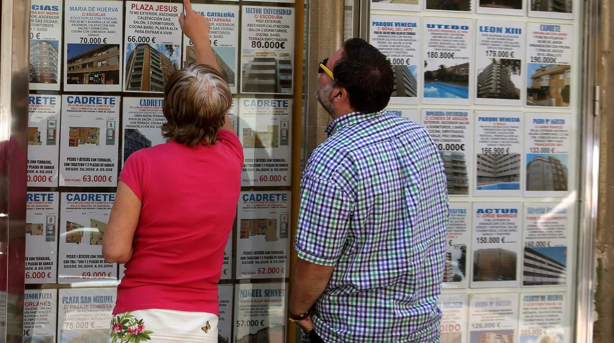 Carteles de pisos en vengta y alquiler en el escaparate de una agencia inmobiliaria de Zaragoza