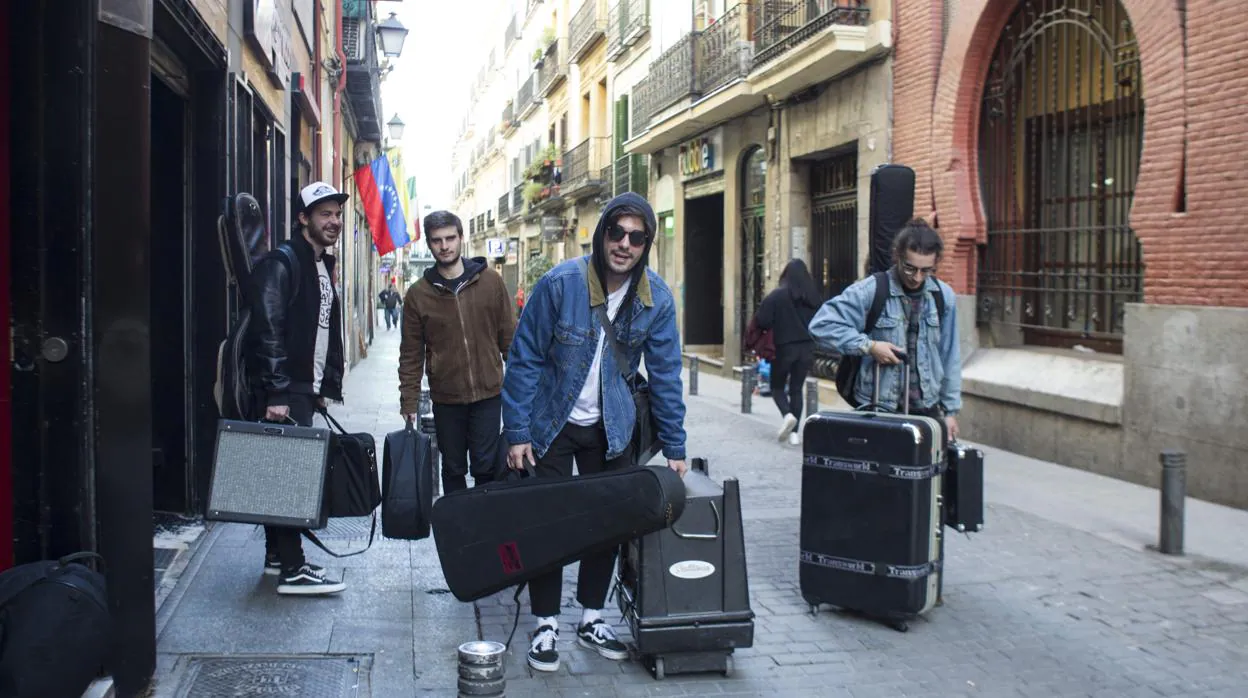 Un grupo carga con sus instrumentos por la calle Jardines, en Madrid Central, para dar un concierto
