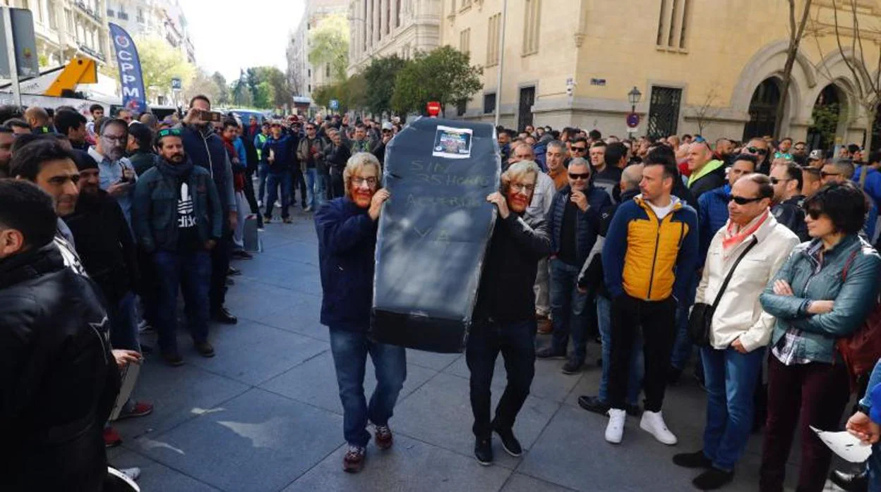 Policías municipales ataviados con una careta de Manuela Carmena portan un ataud a las puertas del Palacio de Cibeles