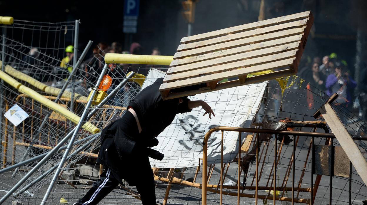 Un independentista radical tirando mobiliario urbano para hacer una barricada en protesta contra Vox