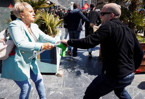 Un manifestante zarandea a una simpatizante de VOX para quitarle una bandera