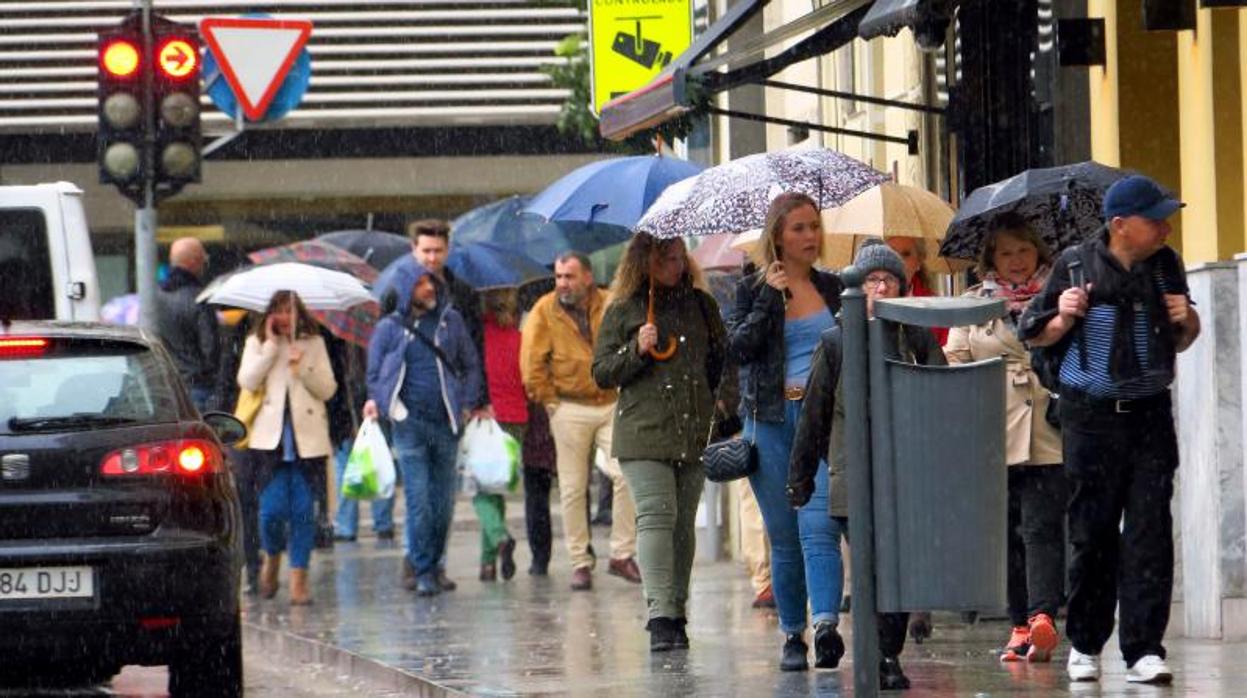 Transeúntes caminando bajo la lluvia por el centro de Alicante