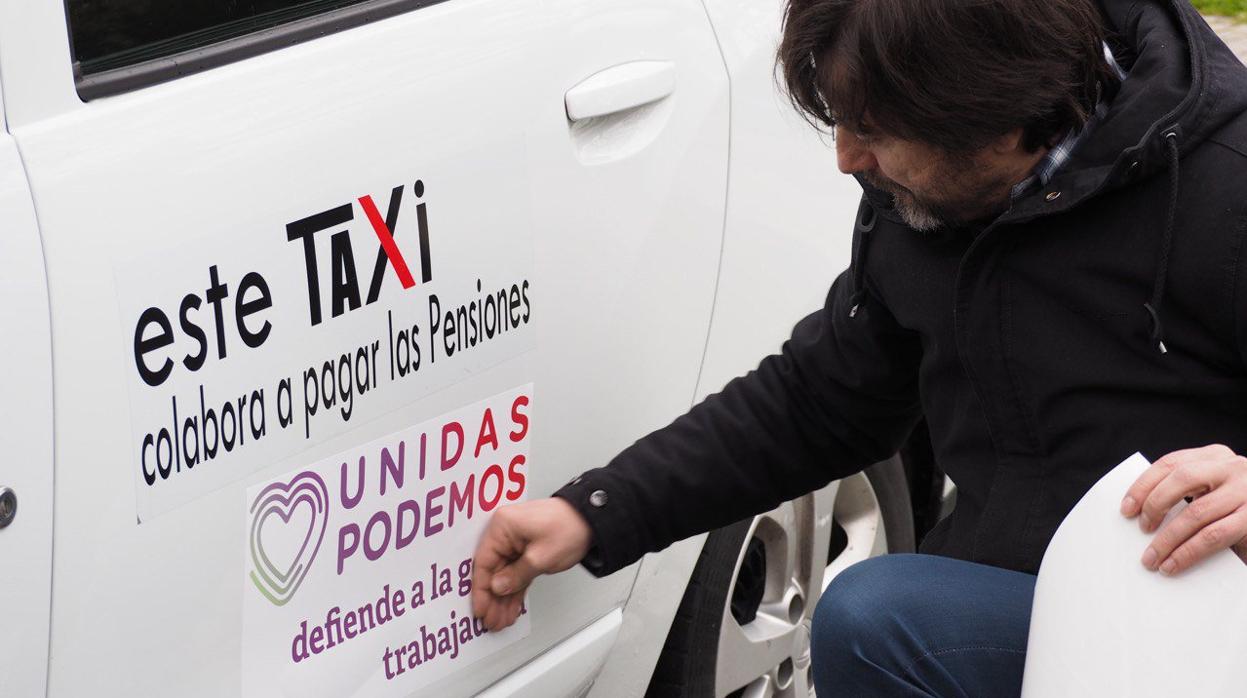 El diputado Rafa Mayoral coloca una pegatina en un taxi