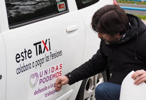 El diputado de Podemos Rafa Mayoral pegando un adhesivo de su partido en un taxi de Madrid
