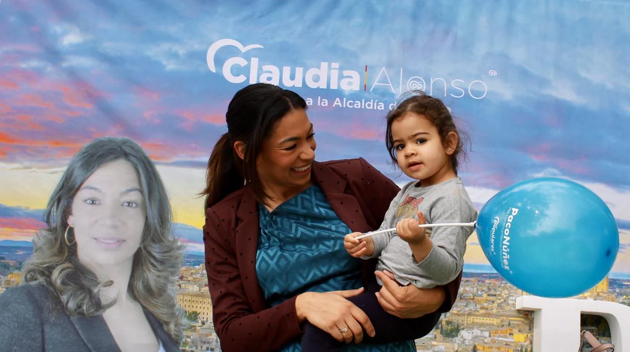 Claudia Alonso, con su hija pequeña, Victoria, en el stand del PP en el paseo de la Vega
