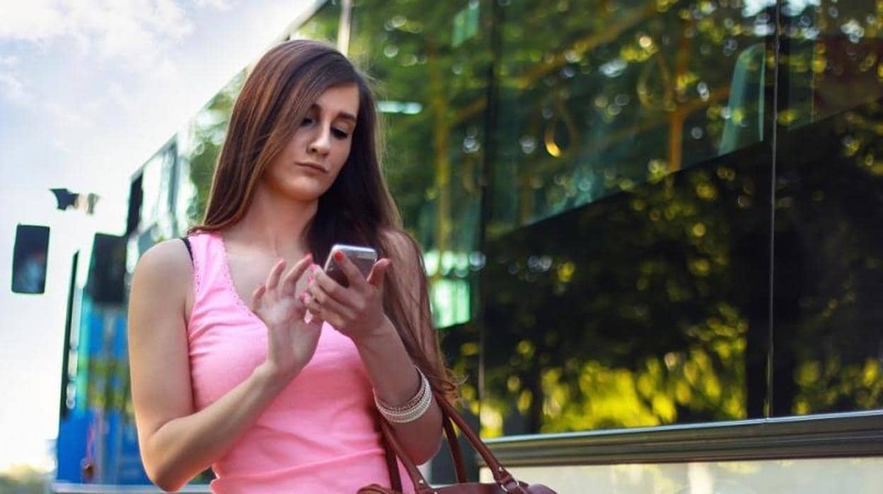 Una joven mira el móvil mientras camina por la calle