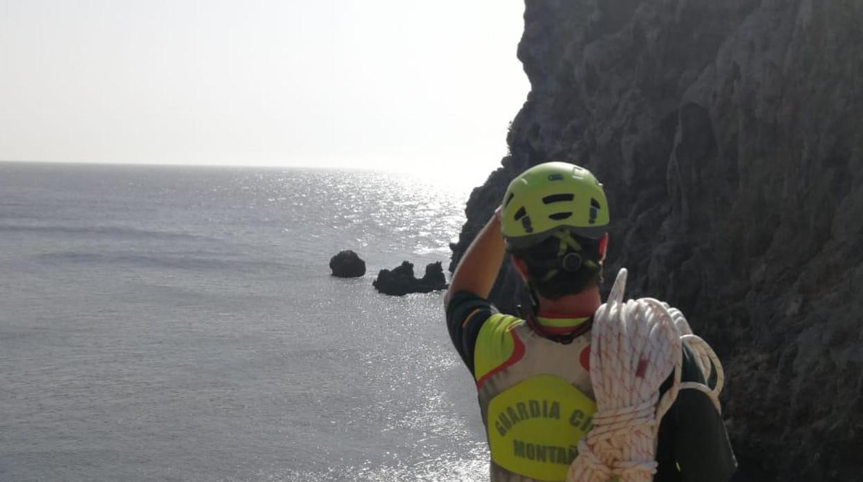Un agente de la Guardia Civil observa la roca desde donde se precipitó el fallecido
