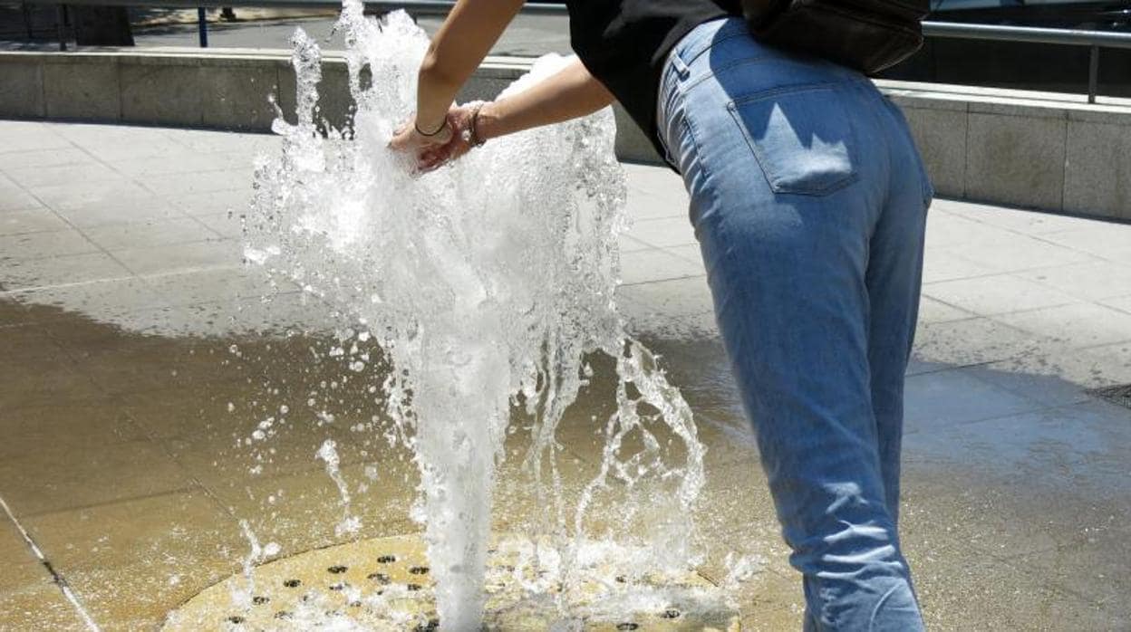 Una transeúnte se refresca por el calor en una fuente en el centro de Alicante