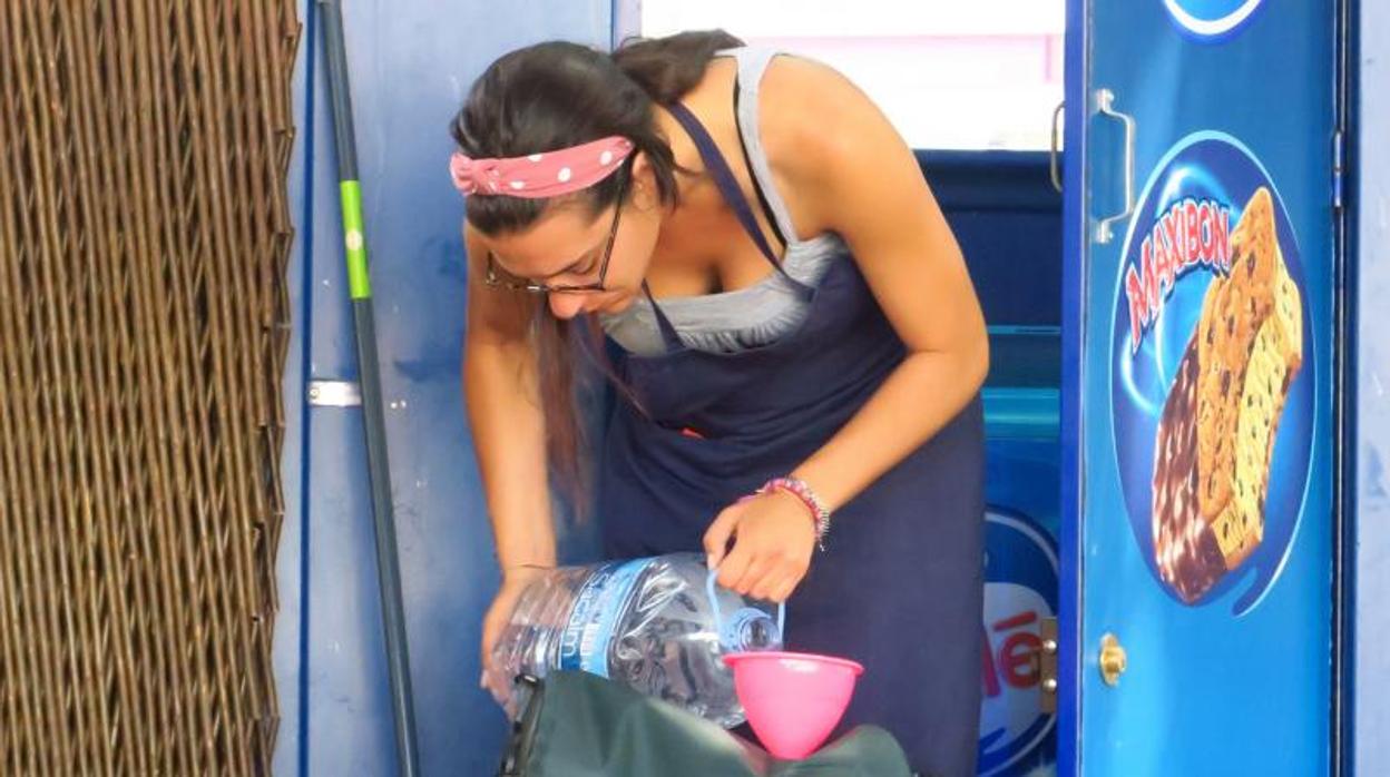 Una mujer llena un depósito de agua portátil en pena de ola de calor