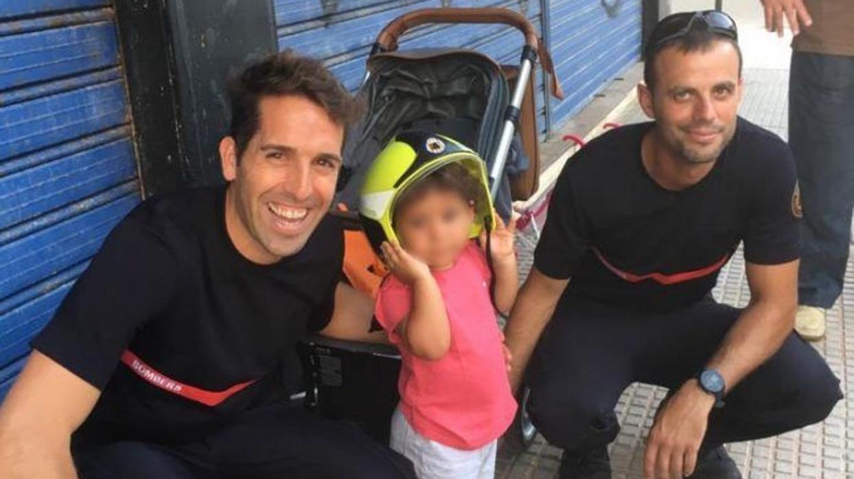 La pequeña, con su casco, con los bomberos que la rescataron