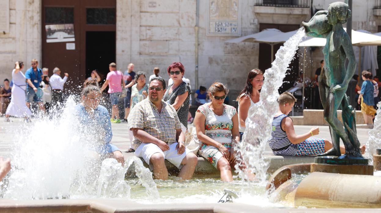 Varias personas se refrescan en el centro de Valencia por las altas temperatura