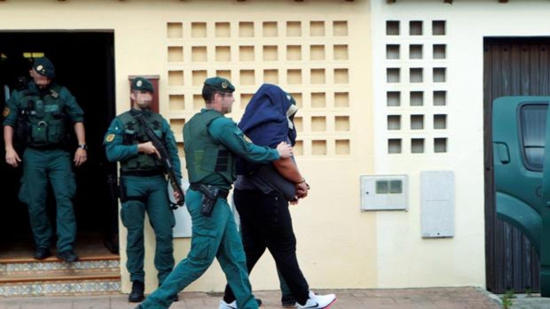 Agentes de la Guardia Civil trasladan a un detenido durante uno de los registros realizados en una vivienda de la calle Espartel en la barriada del rinconcillo en Algeciras (Cádiz)