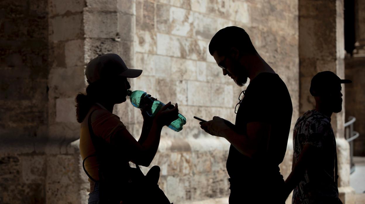 Imagen de una mujer bebiendo agua para sofocar el calor en el centro de Valencia