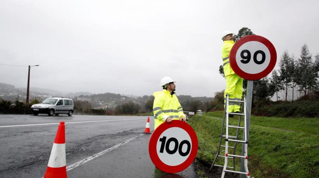 Operarios colocan una señal de tráfico en una carretera gallega