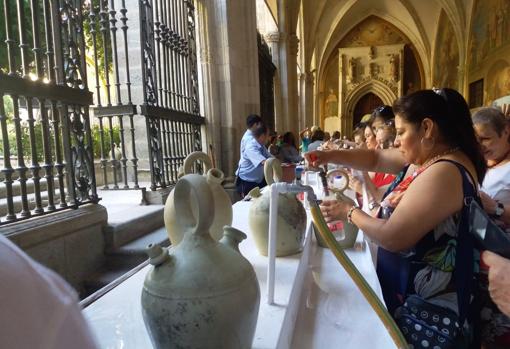 Muchos se llevan a casa agua del claustro en botellas, como la mujer de la imagen