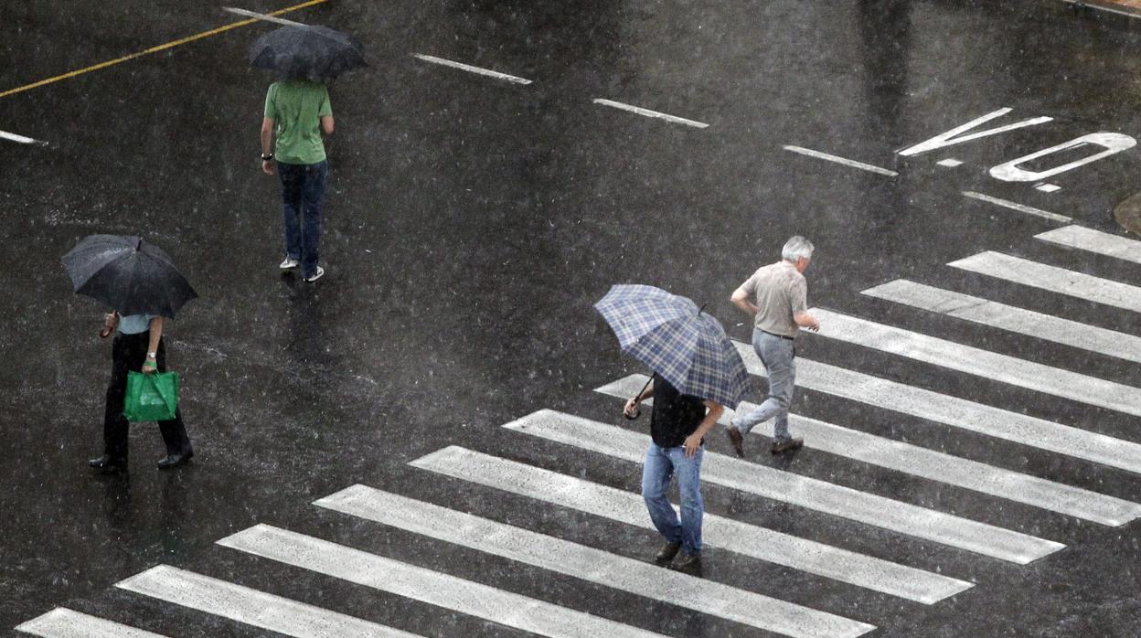 Varias personas se protegen de la lluvia en una imagen de archivo tomada en el centro de Valencia