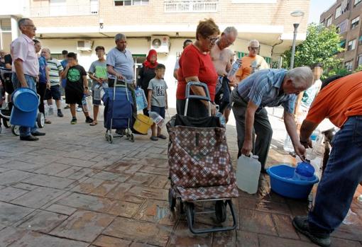 Vecinos de Almoradí cargando agua en garrafas, cubos y barreños para sus hogares