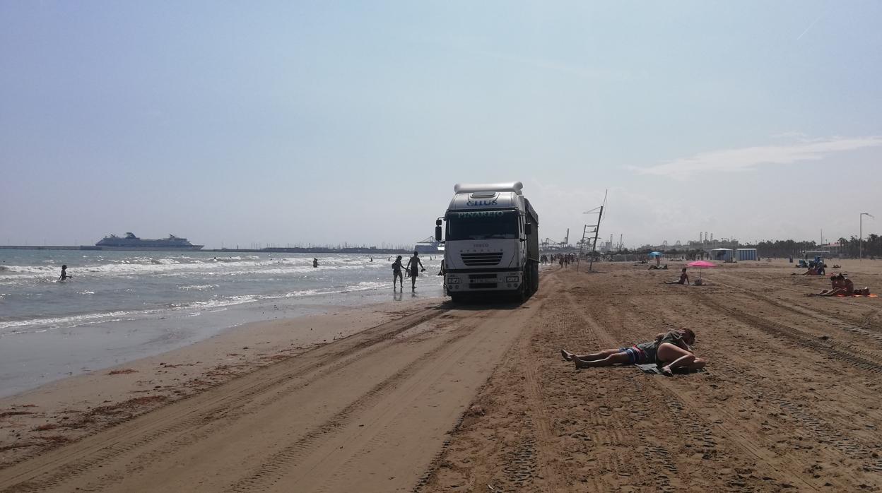 Un camión pasa entre los bañistas, este sábado a la una de la tarde en la playa del Cabanyal de Valencia