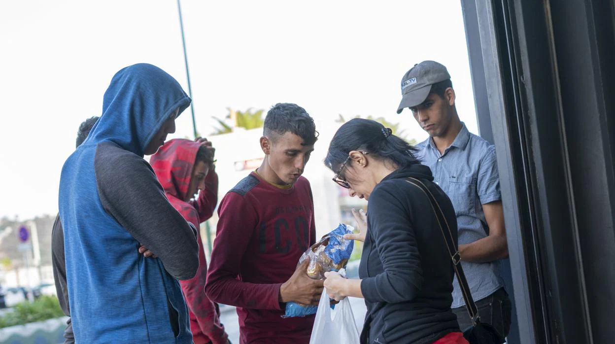 Menores extranjeros pidiendo comida en la puerta de un supermercado, en Ceuta