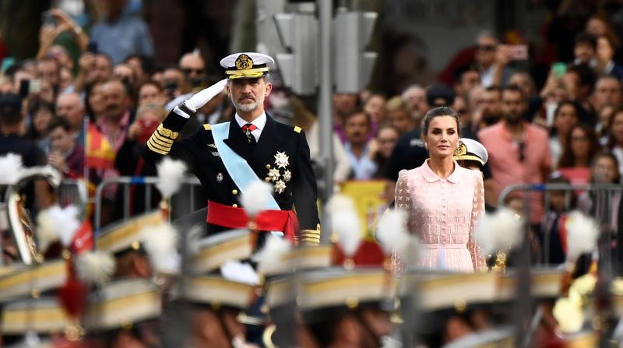 El rey Felipe VI saluda a los soldados junto a la reina Letizia durante el desfile militar del Día Nacional