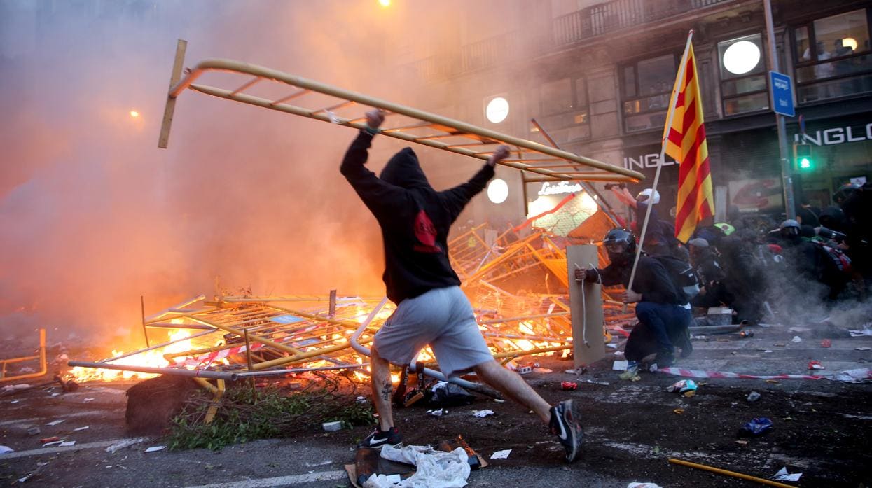 Uno de los radicales lanza una valla al fuego en los disturbios de anteayer en vía Laietana