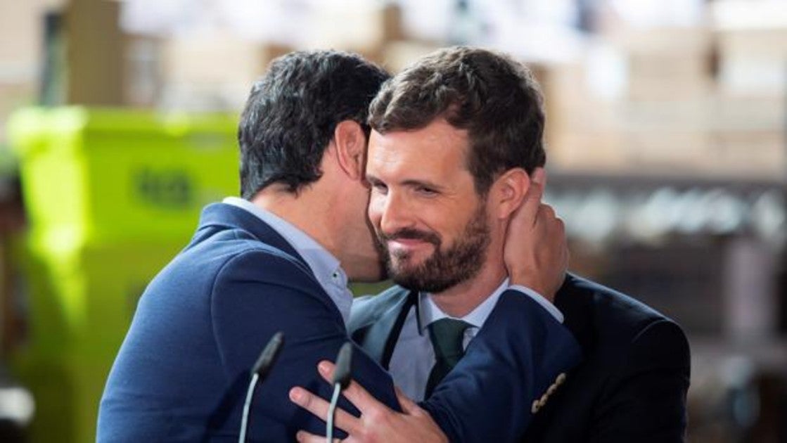 El presidente del PP, Pablo Casado (d), es abrazado por el presidente del PP-A y de la Junta de Andalucía, Juanma Moreno (c), durante un acto en Málaga