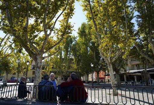 Varias señoras sentadas en el poyete de una tranquila plaza de El Pardo