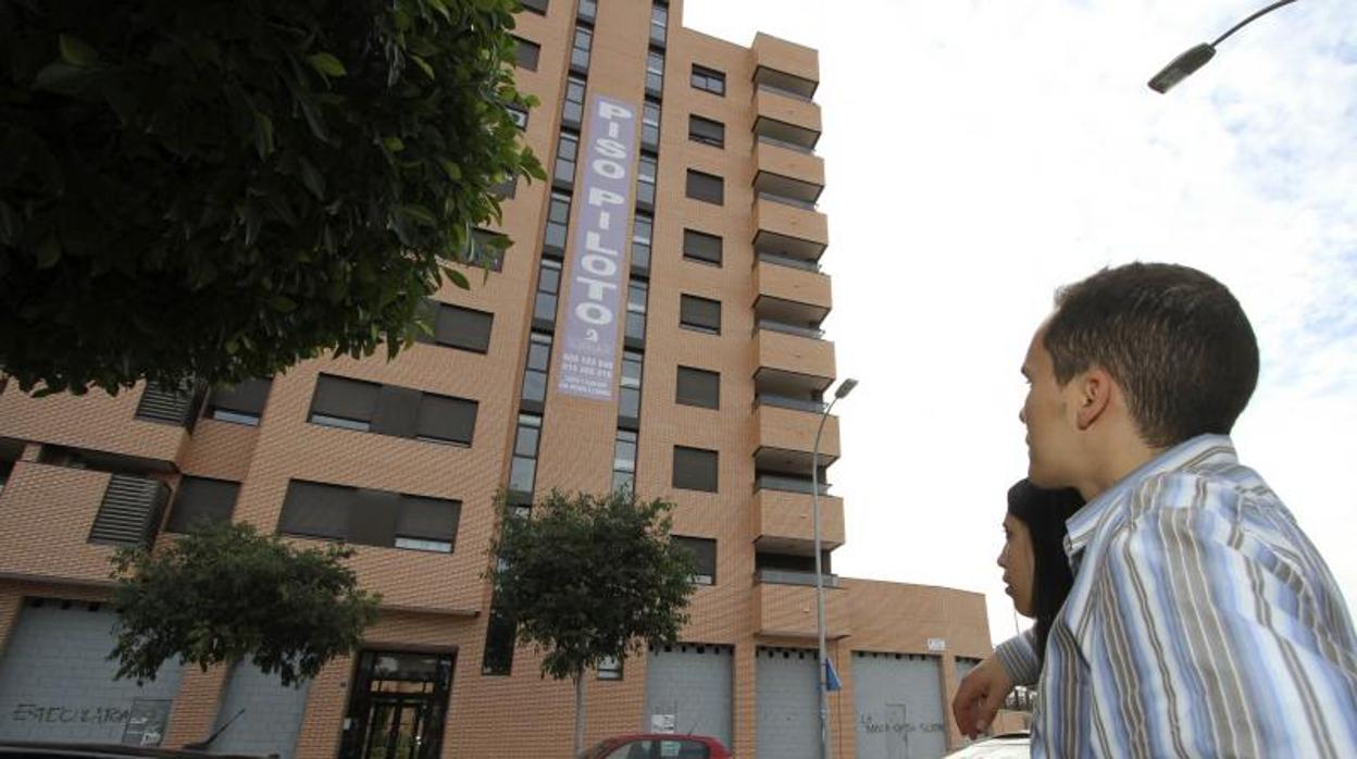 Una pareja de jóvenes observa un edificio de viviendas en venta en Alicante