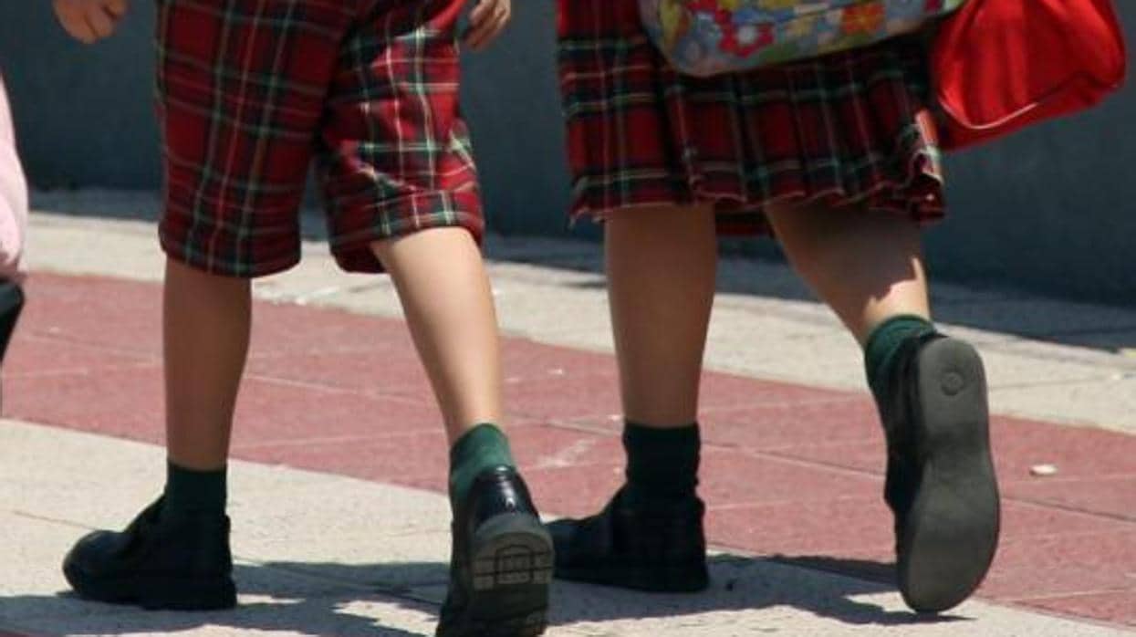 Un niño y una niña con uniforme escolar diferenciado por sexos, él no pantalón y ella con falda, en imagen de archivo