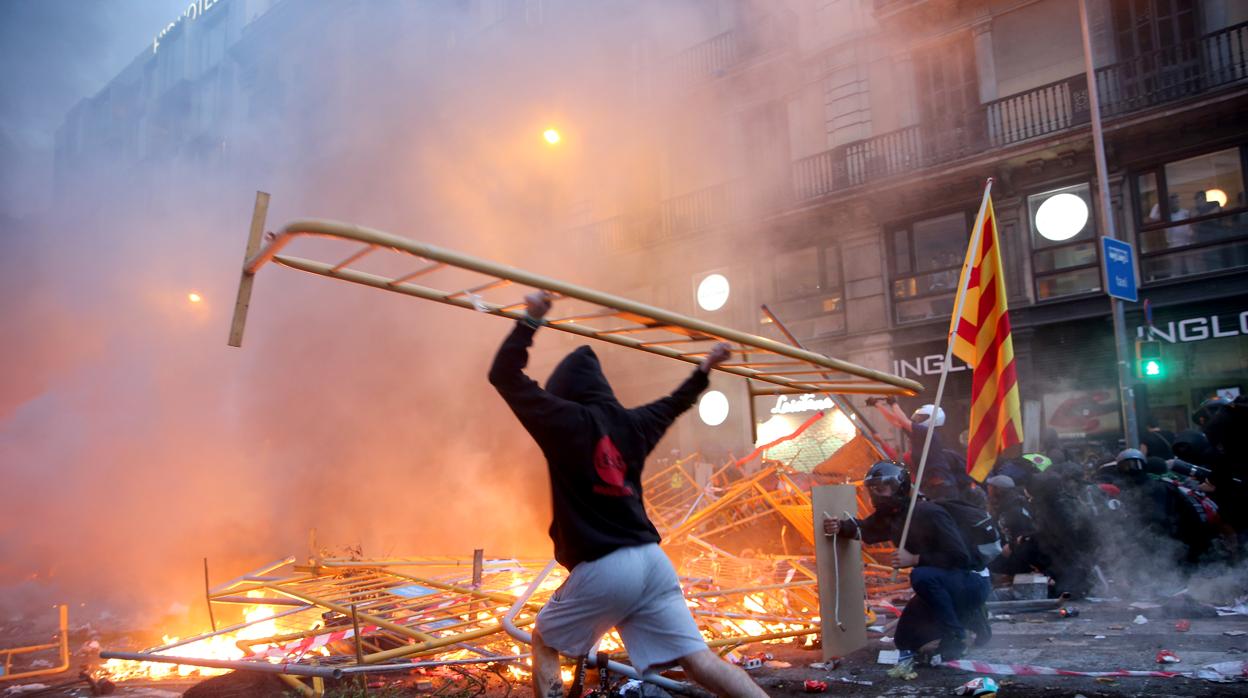 Un manifestante lanza una valla a una barricada en llamas el pasado 18 de octubre en Barcelona