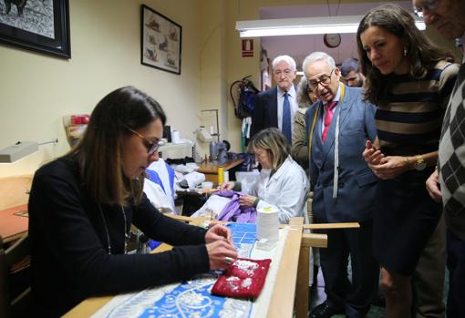 En el taller de la sastrería, una joven bordando la decoración de un traje